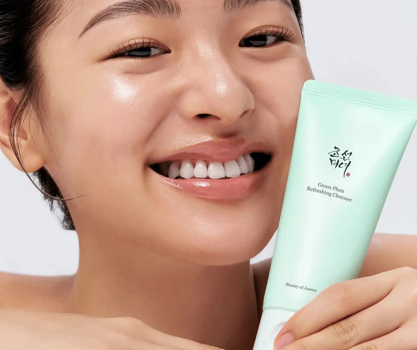 Mujer sonriendo con un limpiador de NanaYoung en la mano, fondo neutro